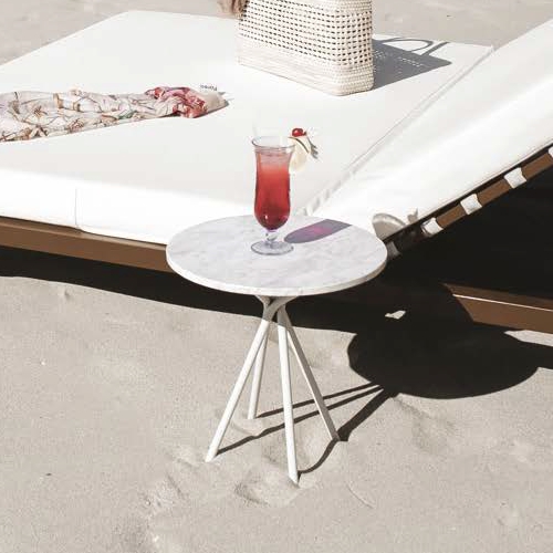 Mesita de apoyo redonda modelo Zipolite en la playa junto a un camastro